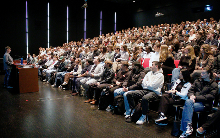 Eine Frau steht an einem rednerpult vor sitzenden Studierenden in einem Hörsaal.