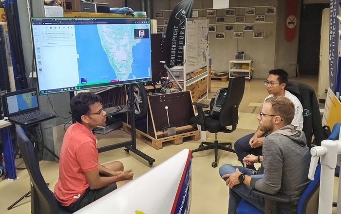 Indische und deustche Studierende sitzen vor einem Bildschirm auf dem ein Karte von Indien zu sehen ist