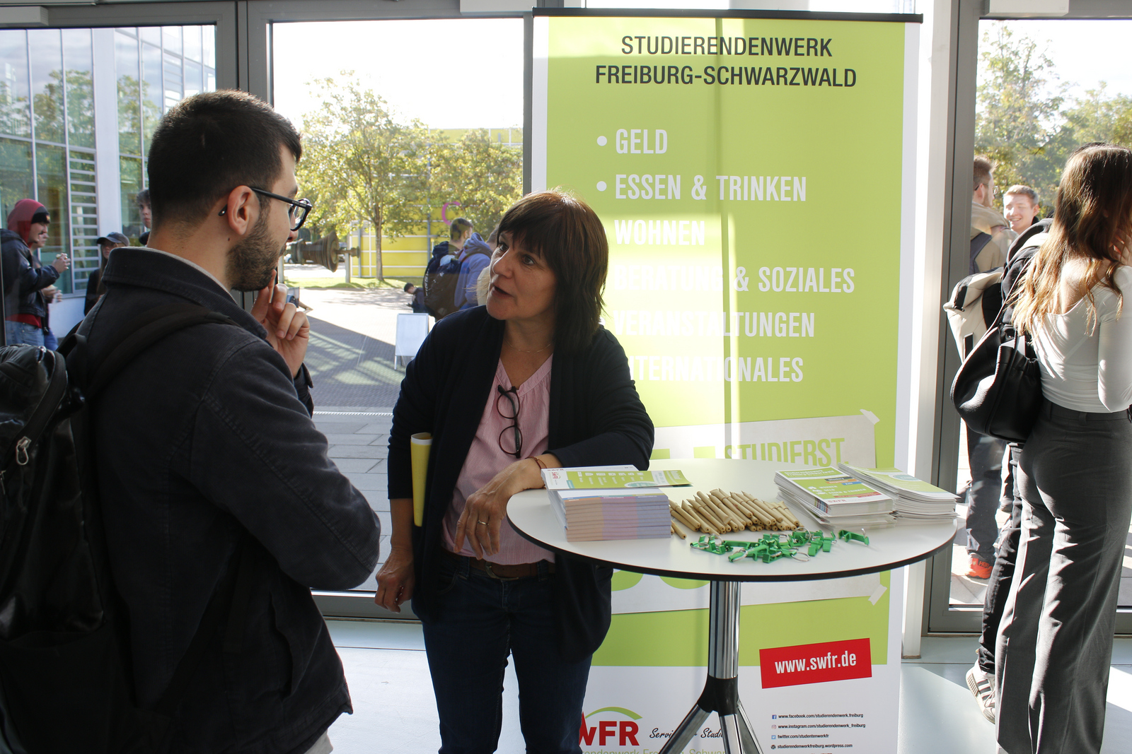 Eine Frau redet einem jungen Mann am Infotisch des Studierendenwerks Freiburg