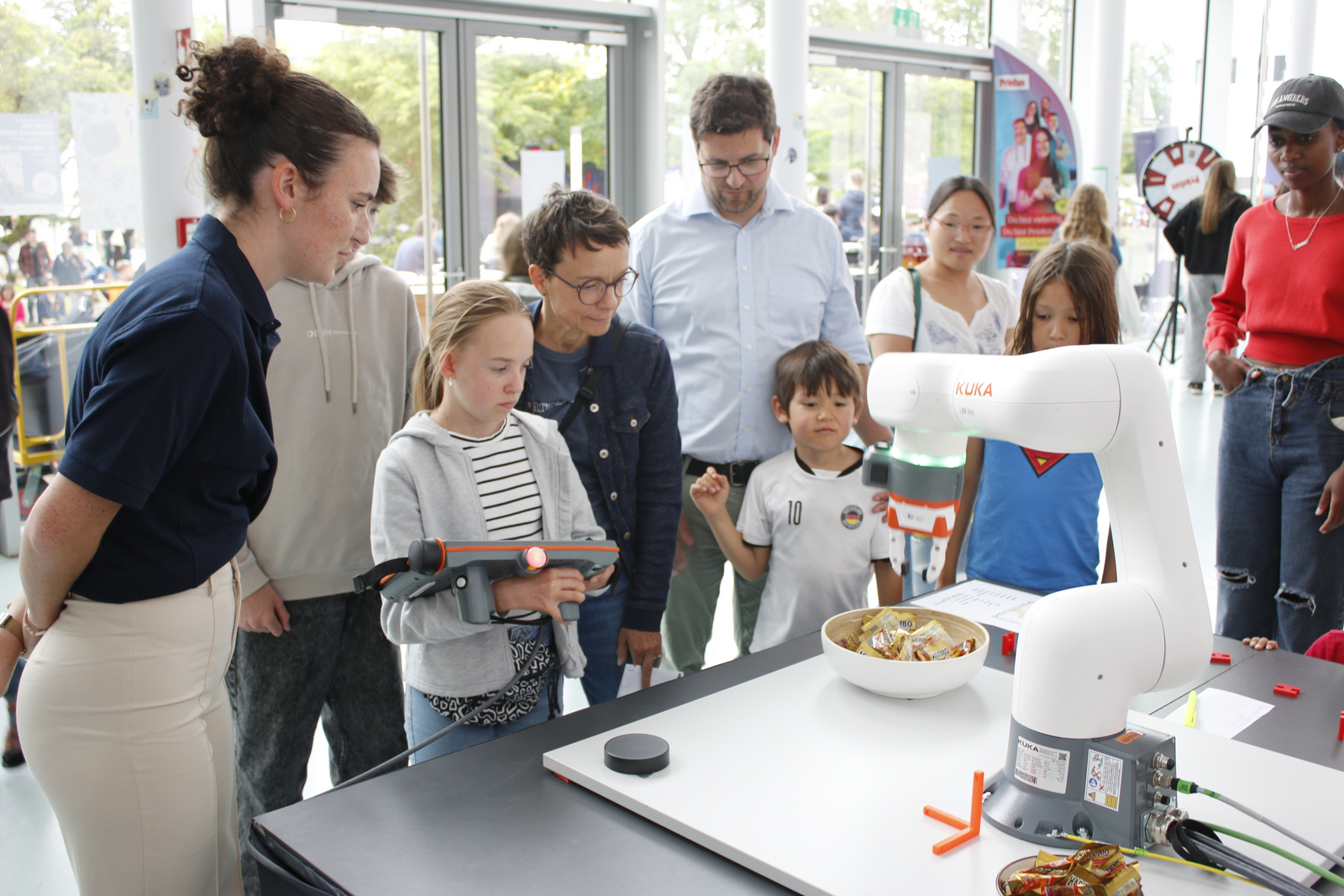 ein Mädchen steuert den Roboterarm während andere ihr zuschauen.