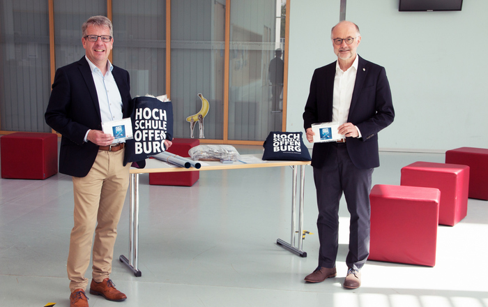 Rektor Prof. Dr. Winfried Lieber (rechts) übergibt Studiendirektor Martin Stern (links), dem stellvertretenden Schulleiter der kaufmännischen Schulen, Masken im Foyer des D-Gebäudes.