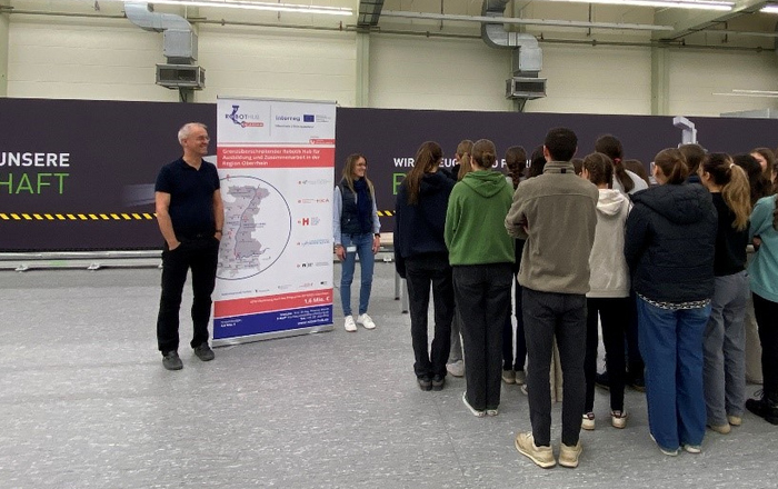 Markus Gapp mit einer Gruppe von Schuler*innen im Robotiklabor