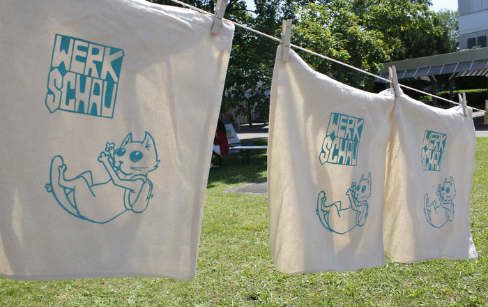 Taschen mit dem Werkschaulogo hängen an einer Leine