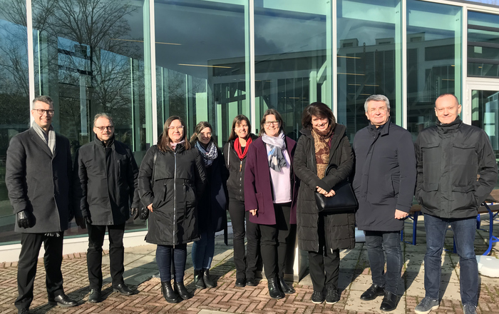 Gruppenfoto bei strahlendem Sonnenschein in Winterjacken vor der Mensa