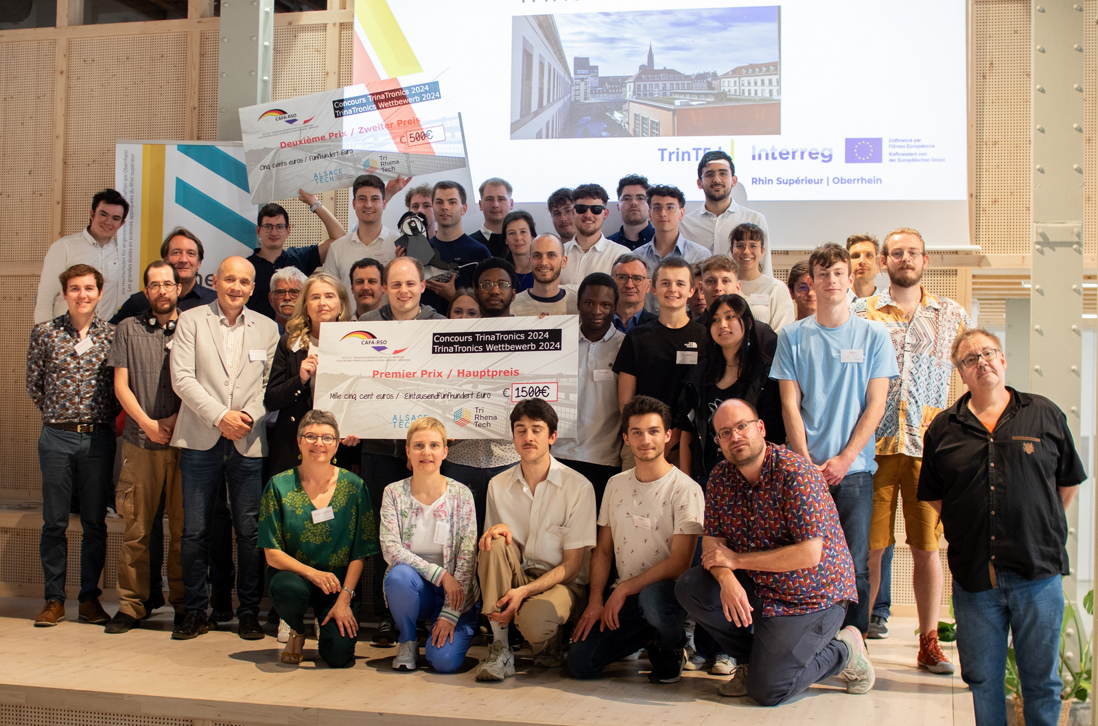 Gruppenfoto aller Teilnehmenden, Betreuenden und Jurymitglieder mit Siegerschecks