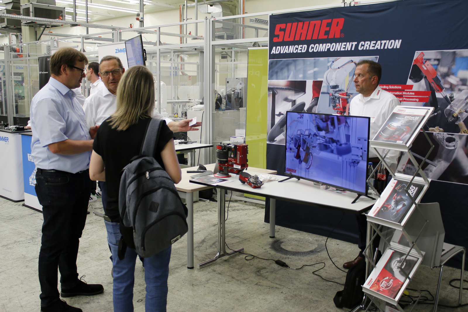 Mehrere Menschen stehen an einem Messestand, einer erklärt etwas