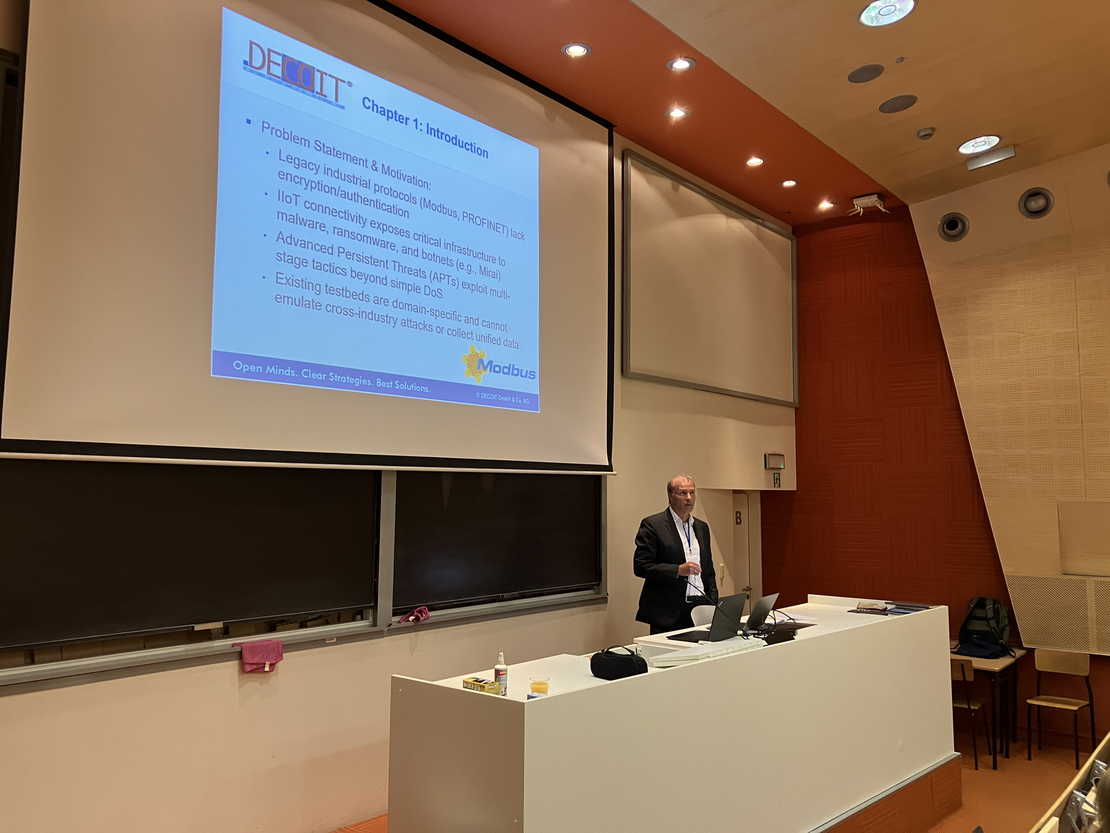 1 Redner am einem Pult vor einer Leinwandpäsentation