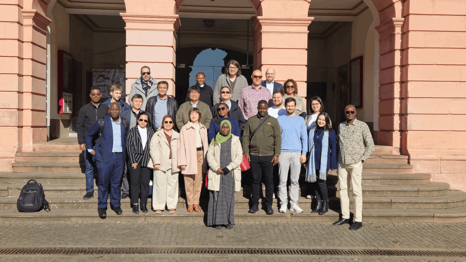 Gruppenfoto auf einer Treppe von dem internationalen Besuch vor einem Gebäude