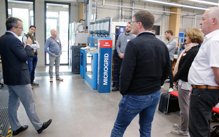 Eine Gruppe Menschen steht um eine MicroGrid-Anlage herum