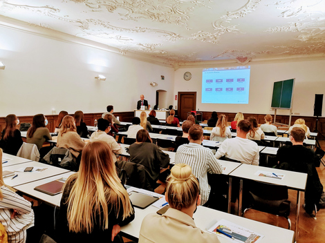 Prof. Dr. Andreas Klasen steht an einem Pult vor den sitzenden Erstsemestern.