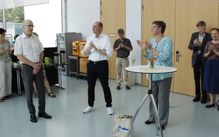 Andreas Christ, Stephan Trahasch und Elke Mackensen stehen in einem Halbkreis um eine Stehtisch im Foyer von Gebäude D und um sie herum weitere Menschen