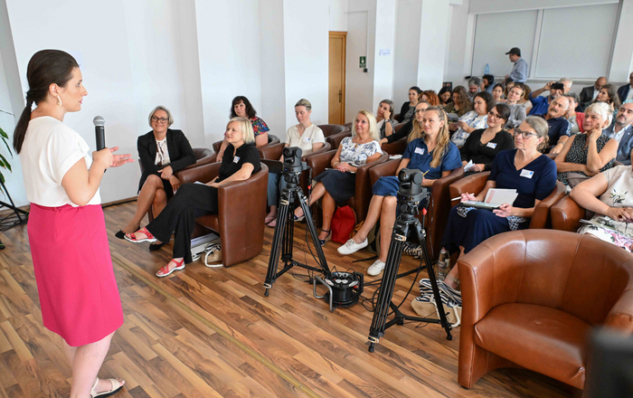 Eine Frau steht vor sitzenden Zuhörenden