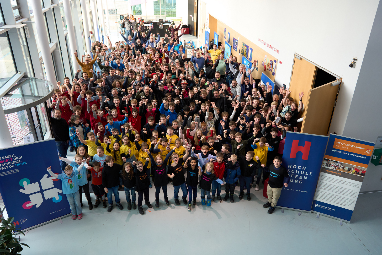 Gruppenfoto alle Beteiligten von oben jubelnd im Foyer
