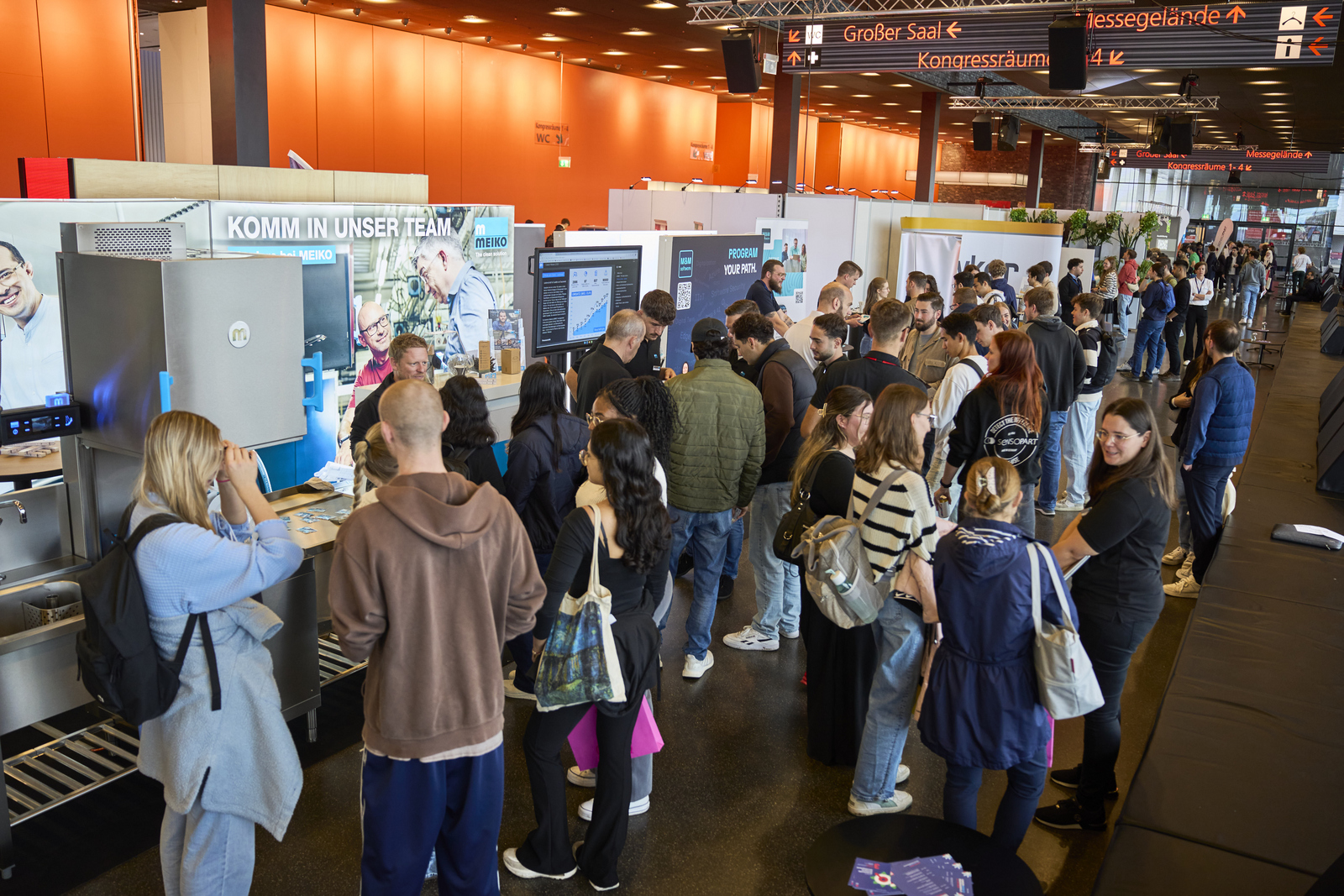 Junge Leute an Messestände in einer Kongresshalle