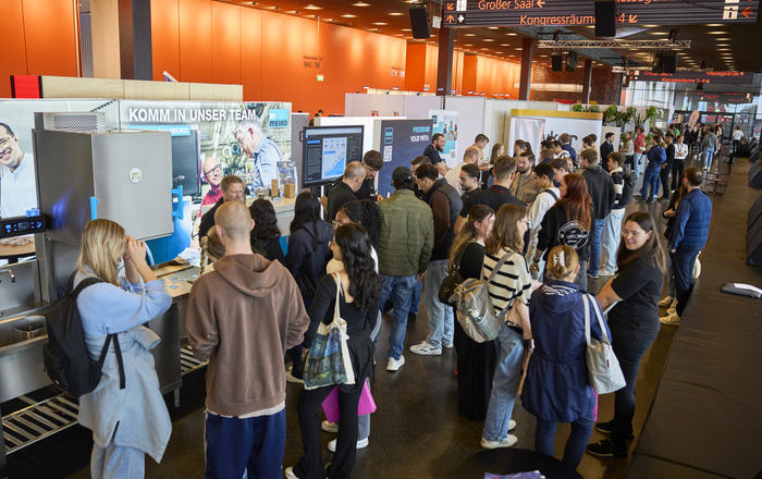 Junge Leute an Messestände in einer Kongresshalle