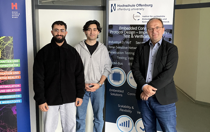 3 Personen neben einem RollUp des Instituts