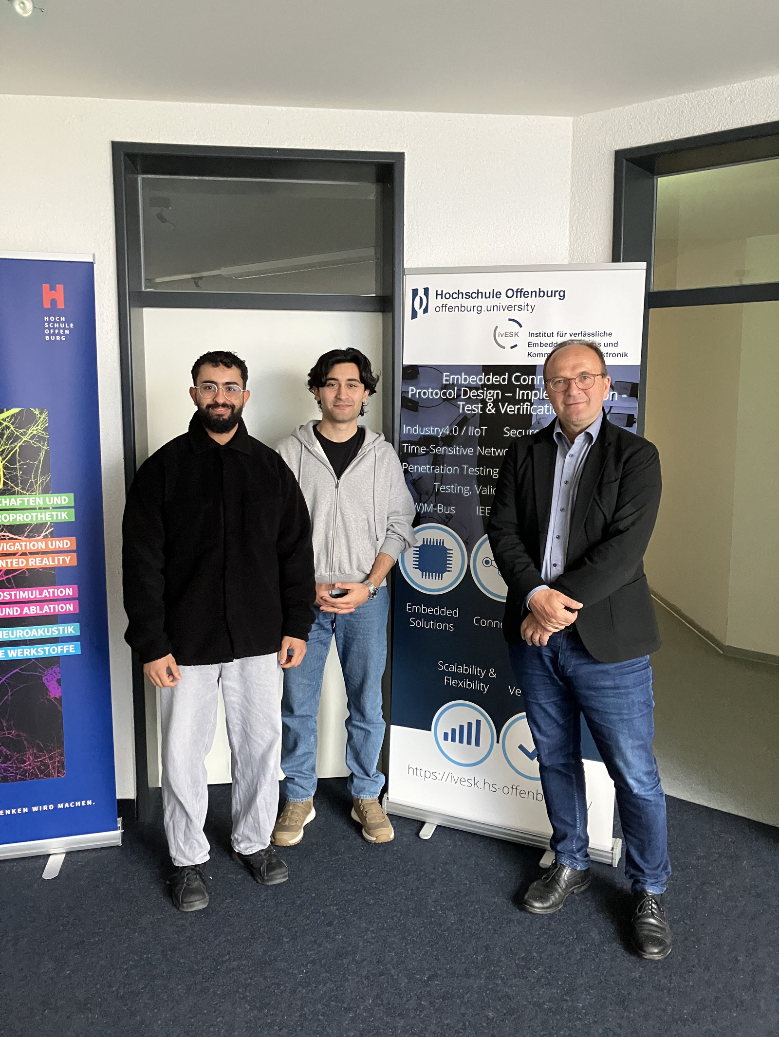 3 Personen neben einem RollUp des Instituts