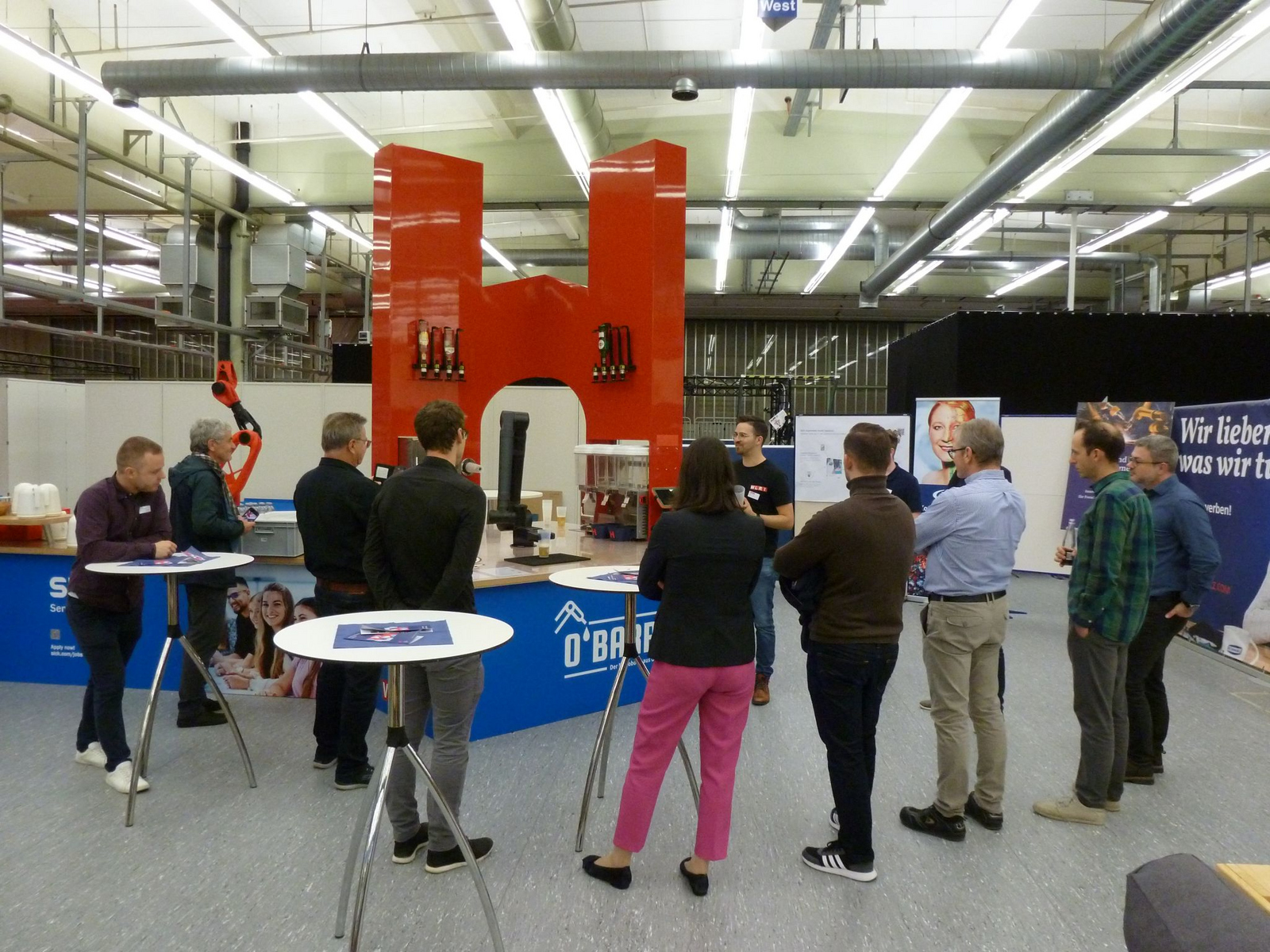 A person demonstrating a robot on a bar to a group of people