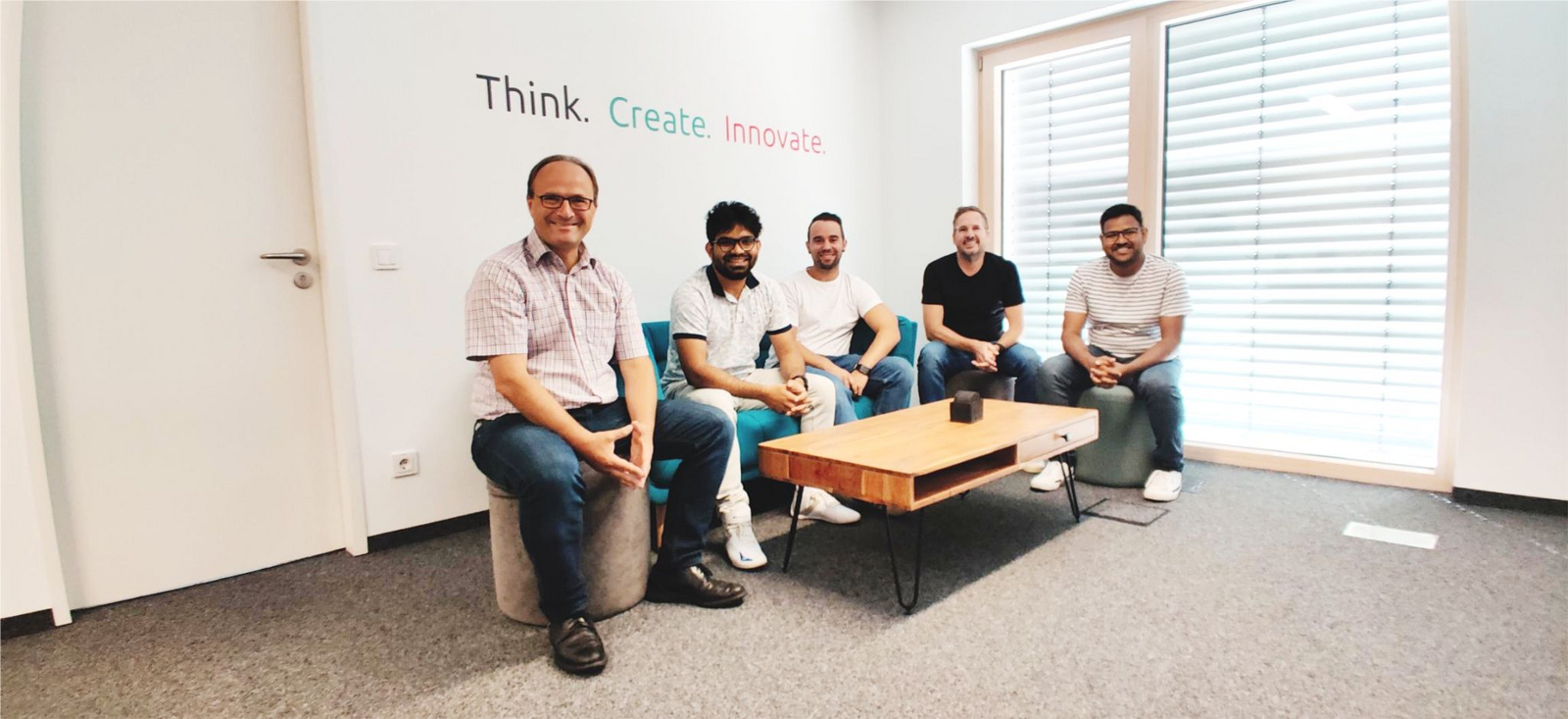 Die Projektbeteiligten sitzen unter der Überschrift Think. Create. Innovate an einem Couchtisch.