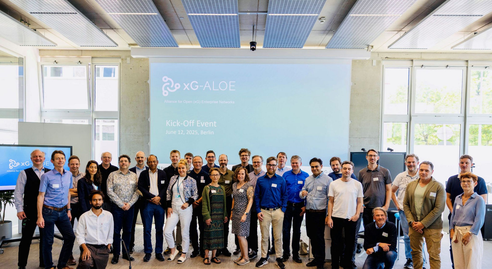 Die Teilnehmer des KickoffMeetings als Gruppe vor der Leinwand