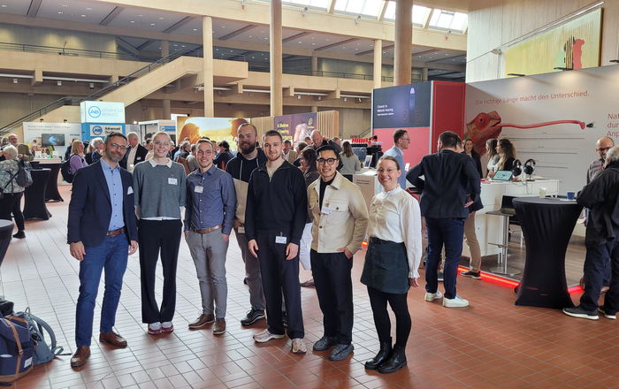 Gruppenfoto umgeben von Messeständen und -besuchenden