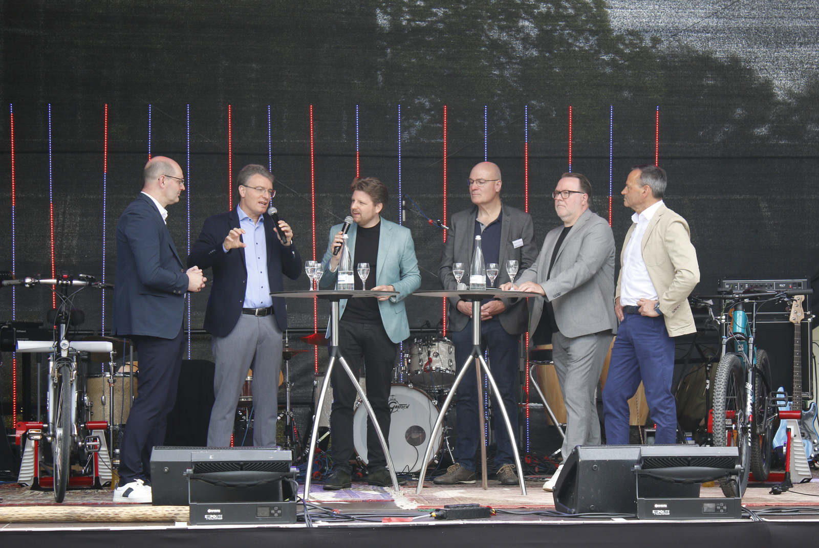 Die Redner stehen an Stehtischen auf der Bühne