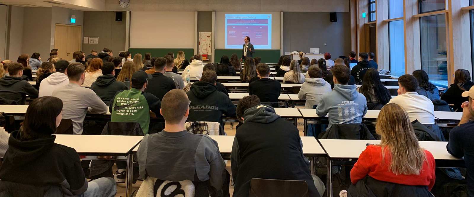 Professor steht vor sitzenden Studierenden