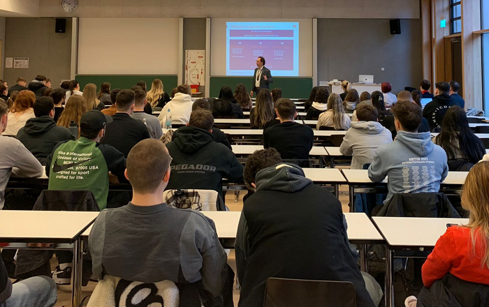 Professor steht vor sitzenden Studierenden