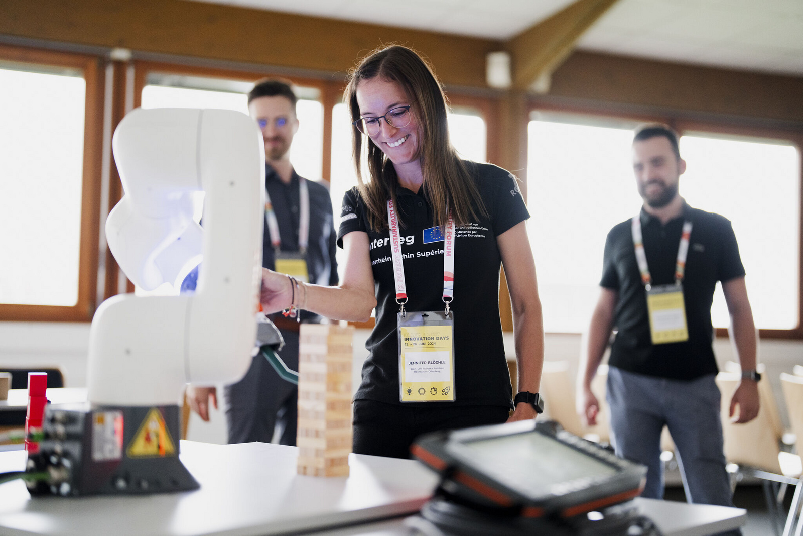 A person operating a robotic arm while two other people watch
