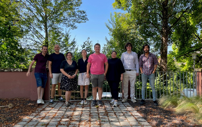 Gruppenfoto der Forschungspartner KINLI. Man sieht acht Personen stehend vor blauem Himmel und grünen Bäumen.