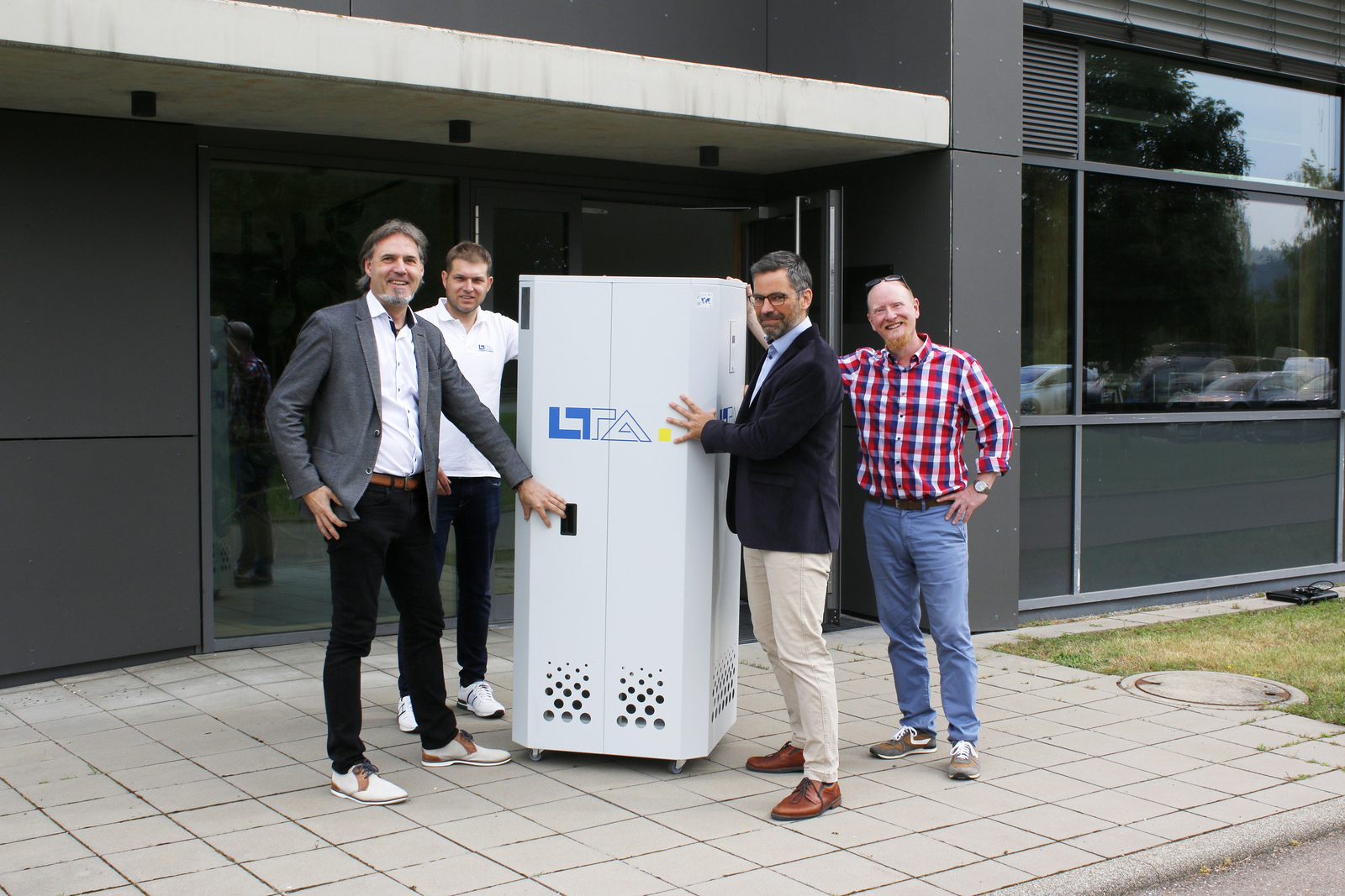 Vier Männer stehen um den mobilen Luftfilter herum und schieben ihn ins POIM