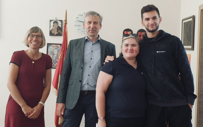 Vier Personen stehen nebeneinander in einem Büro