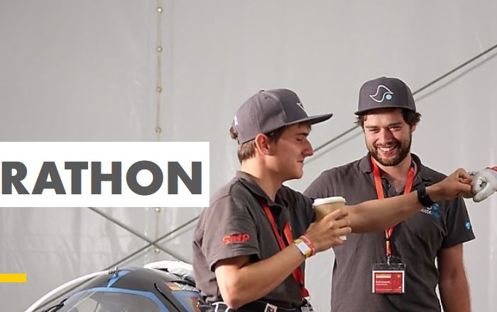 Das offizielle des Shell eco-marathon Quizes mit dem drei Mitgliedern des Teams Schluckspecht, die nebem den Schluckspecht stehen und sich geballten Fäusten gegenseitig gratulieren. 