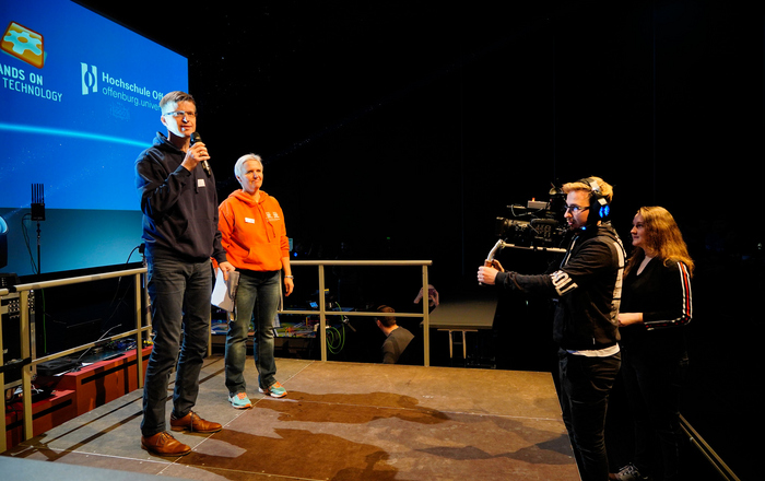 Prof. Dr. Jan Münchenberg, Nicole Diebold und das Mediateam (von links) bei den Vorbereitungen für das FLL-Finale Zentraleuropa auf der Bühne. 