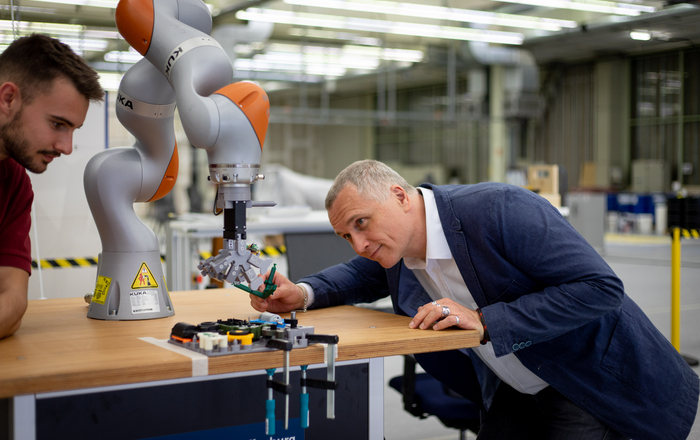 Prof. Dr. Thomas Wendt (rechts) und ein Mitarbeitender (links) arbeiten an einem Koboter 