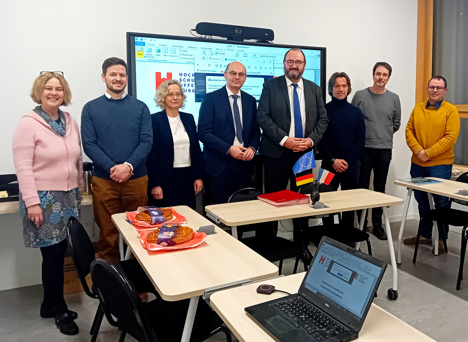 Gruppenfoto die Beteiligten stehen vor einem Bildschirm