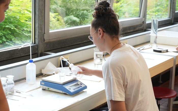 Ein Mädchen untersucht eine Wasserprobe mit Mikroplastik