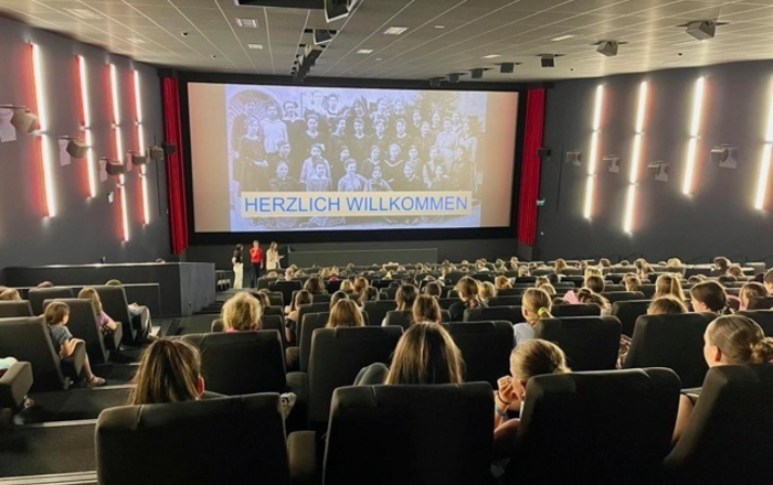 Schülerinnen sitzen im Kino-Saal. Auf der Leinwand läuft der Film