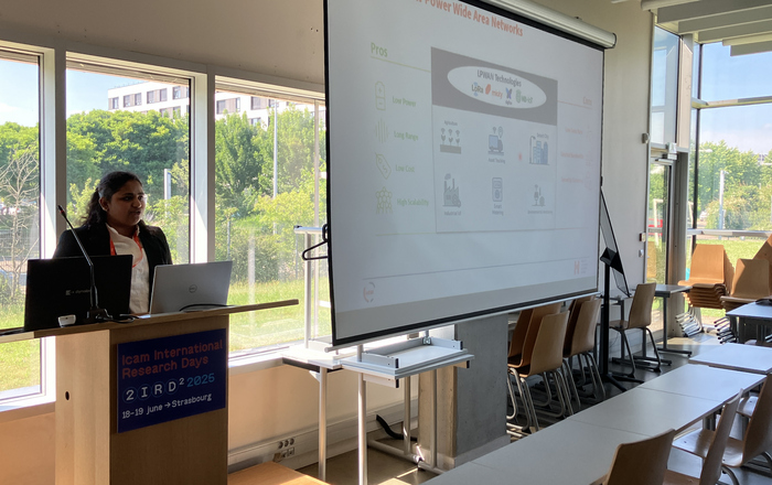 eine Person am Rednerpult neben einer Leinwand