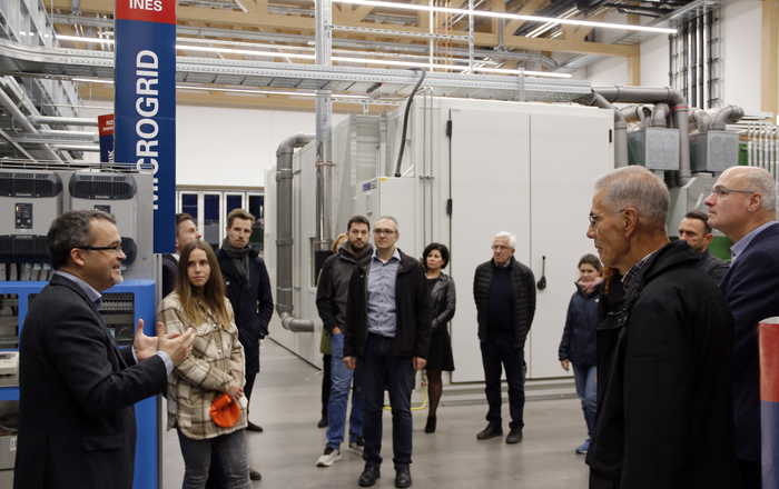 Die Pesonen stehen im Technikum des RIZ, links sind Stromverteilerkästen und im Hintergrund die Klimakammer und Teile einer Heizungsanlage zu sehen