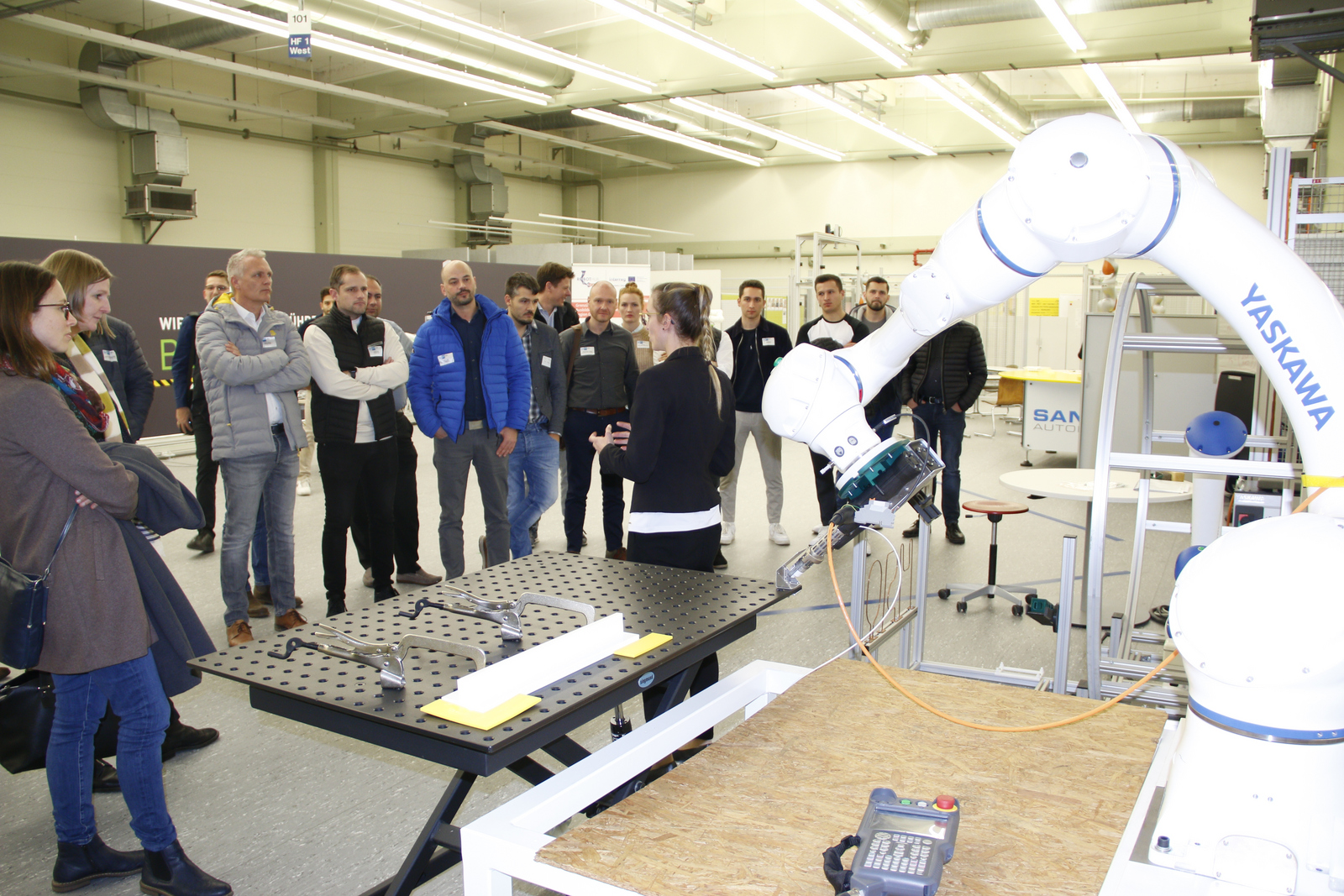 Besuchergruppe schaut Roboter bei der Arbeit zu