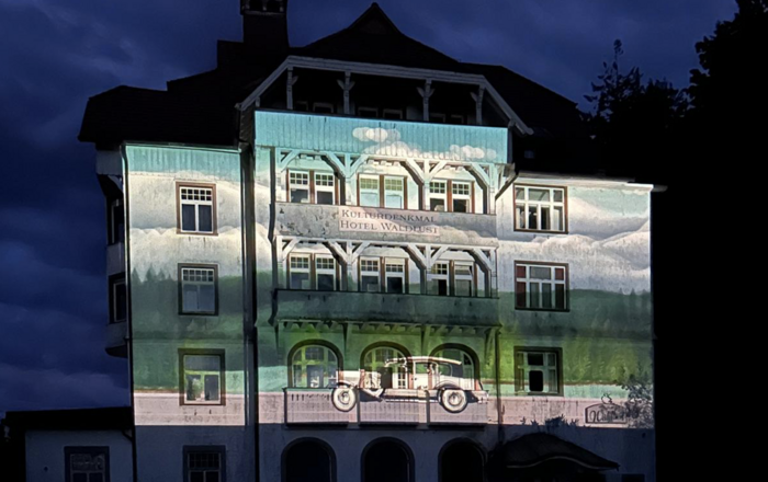 An die Außenfassende eines alten Hotelgebäudes werden in der Nacht Bilder aus dessen 120-jähriger Geschichte projiziert