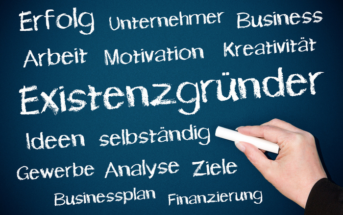 Eine Tafel auf die eine Hand schon ganz viele Wörter passend zum größten Wort Existenzgründer geschrieben hat.