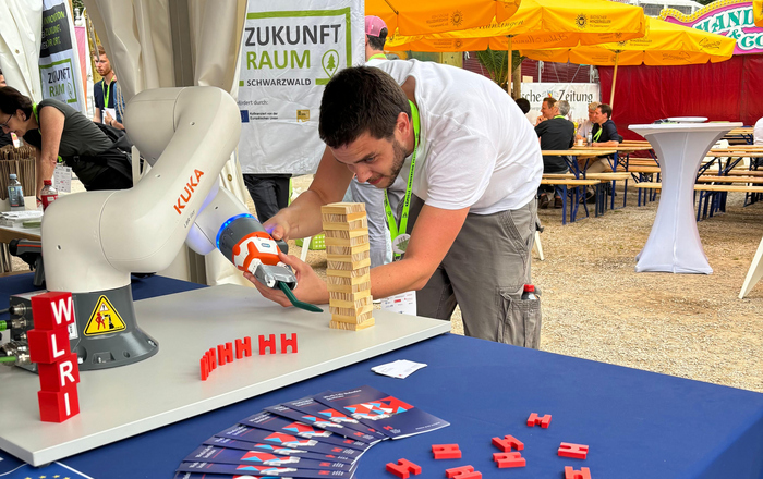 Ein Mann beugt sich an einem Stand im Freien über einen Roboterarm