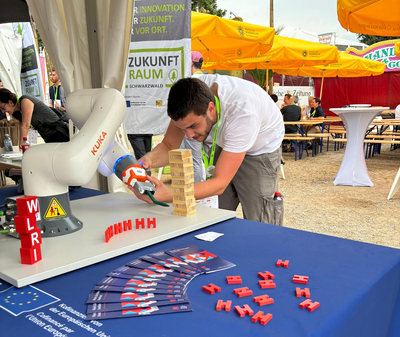 Ein Mann beugt sich an einem Stand im Freien über einen Roboterarm