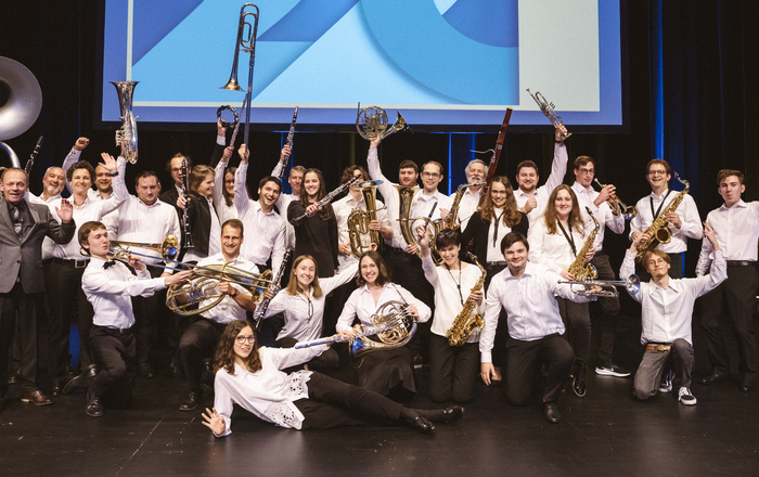 Gruppenfoto des Hochschulorchester, das jubelnd seine Instrumente präsentiert