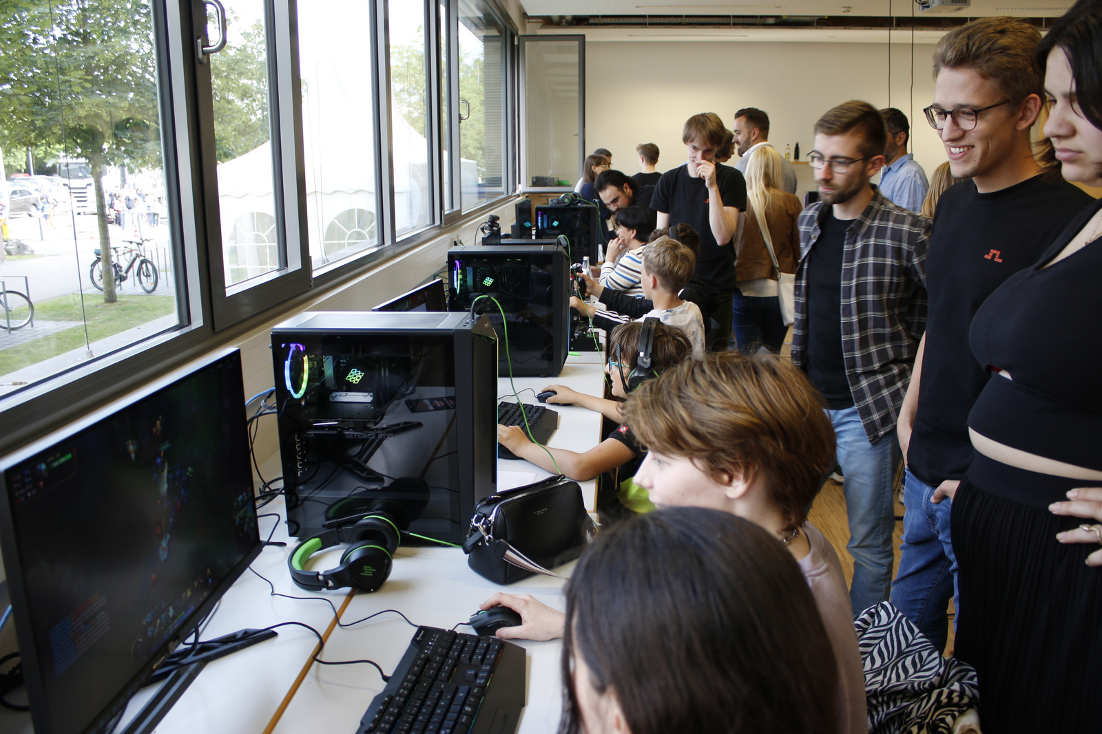 Junge Menschen sitzen und stehen an Rechner und spielen Computerspiele