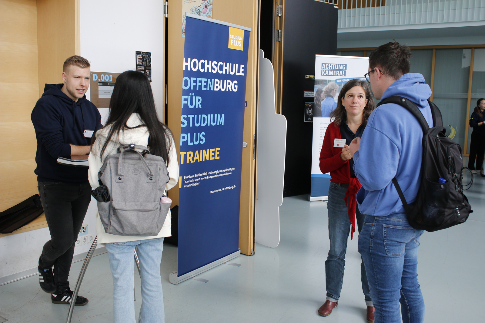eine junge Frau und ein junger Mann informieren sich bei einem Studierenden und einer Frau über StudiumPLUS Trainee