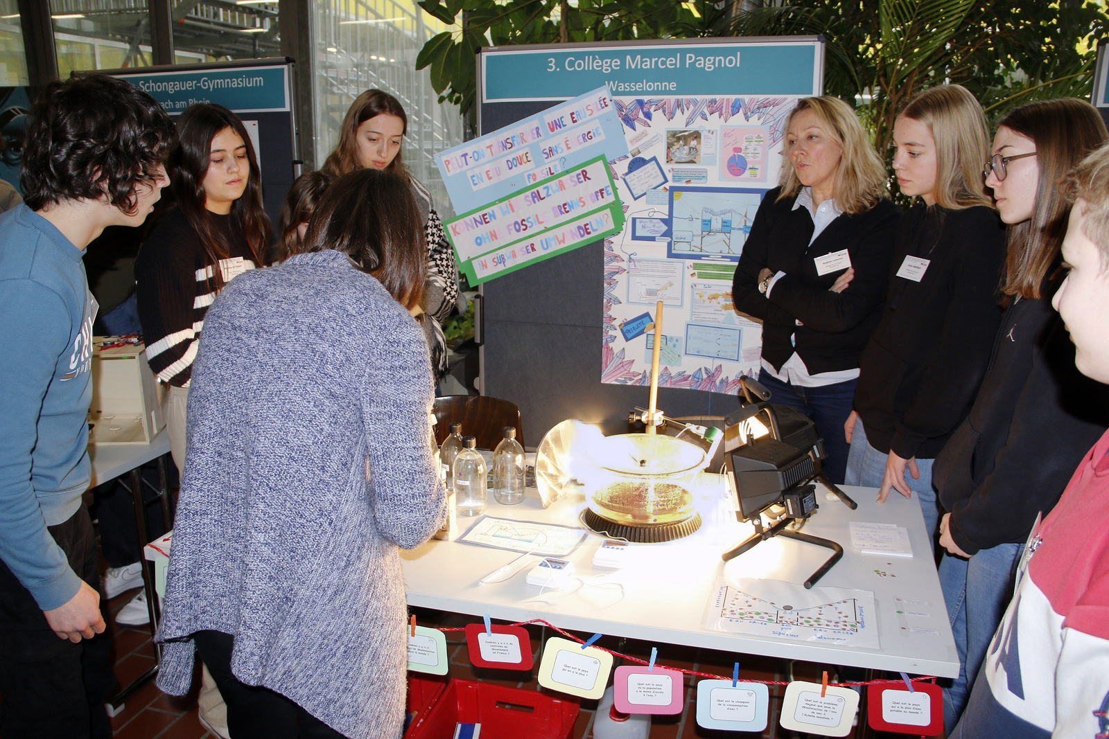 Schülerinnen und Schüler machen mit einer Besucherin Wasserversuche