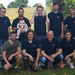Teamfoto mit Robotern unter einem Baum auf einer Wiese
